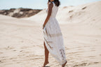 Woman in a white lace dress standing on sandy dunes