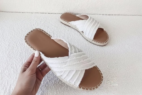 White woven sandals on a textured white surface