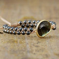 Bracelet with black beads and a goldstone bead on a wooden surface