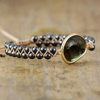 Bracelet with black beads and a goldstone bead on a wooden surface