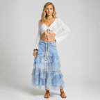 Woman wearing a white top and blue tiered skirt on a plain background