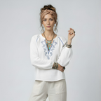 Woman wearing a white blouse with embroidery and beige pants on a light gray background