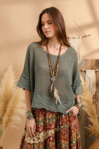 Woman wearing a green textured top and pants against a plain background