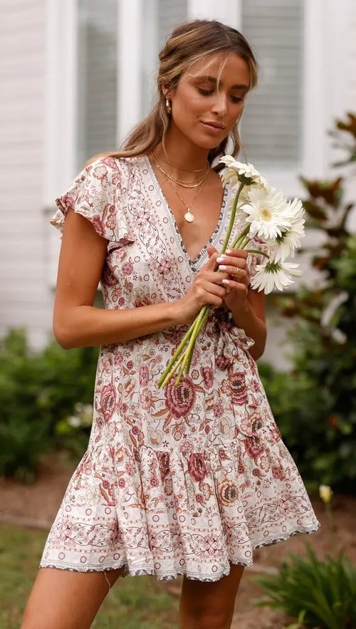 Woman in a floral dress holding flowers outdoors