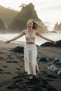 Woman with outstretched arms on Piha  beach with rocky mountains in the background
