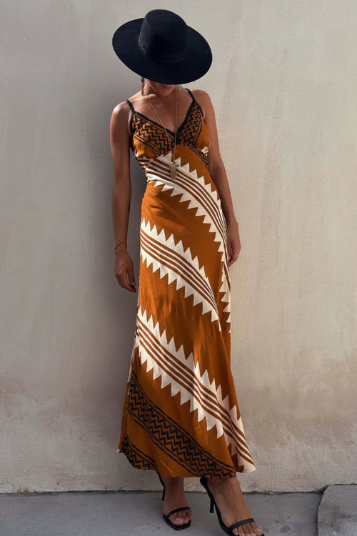 Woman wearing a patterned dress and black hat against a plain background